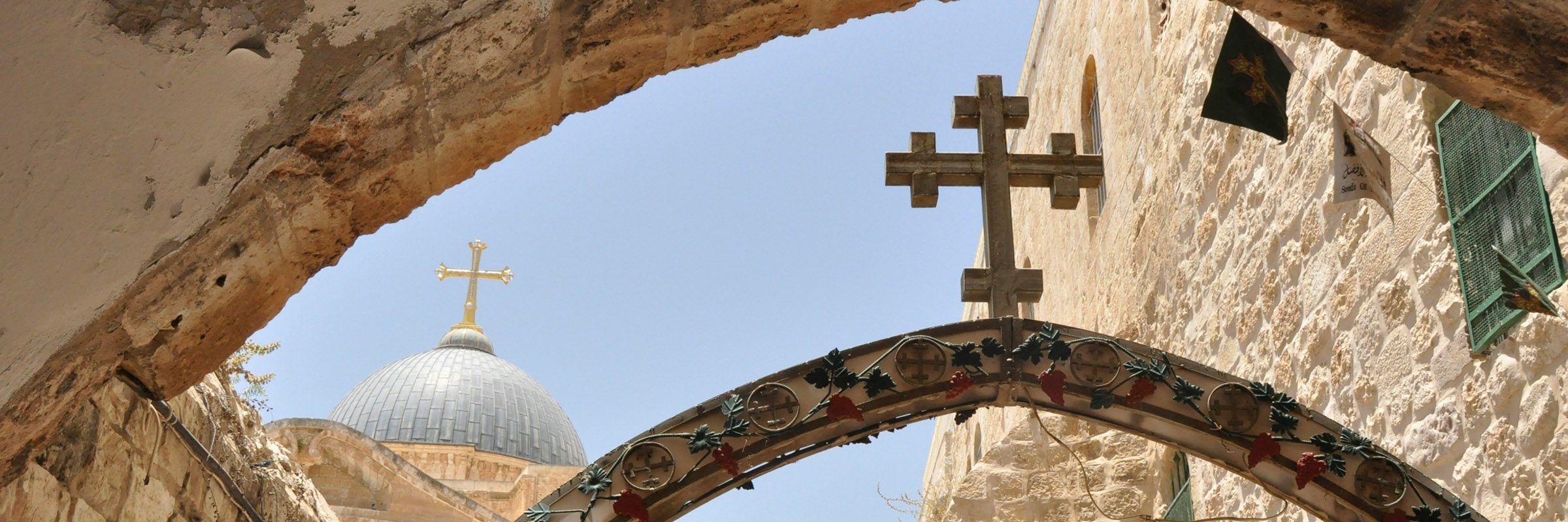 The interior of the Church of the Holy Sepulchre in Jerusalem, with warm light filtering through ancient stone arches as pilgrims gather around the Edicule