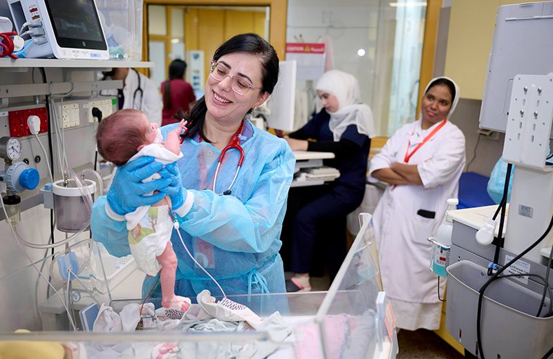 A nurse at Caritas Baby Hospital in Bethlehem gently holds an infant while monitoring medical equipment