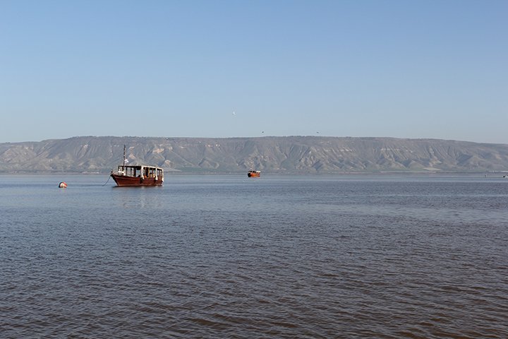 Pilgrims on a boat crossing the Sea of Galilee at sunrise